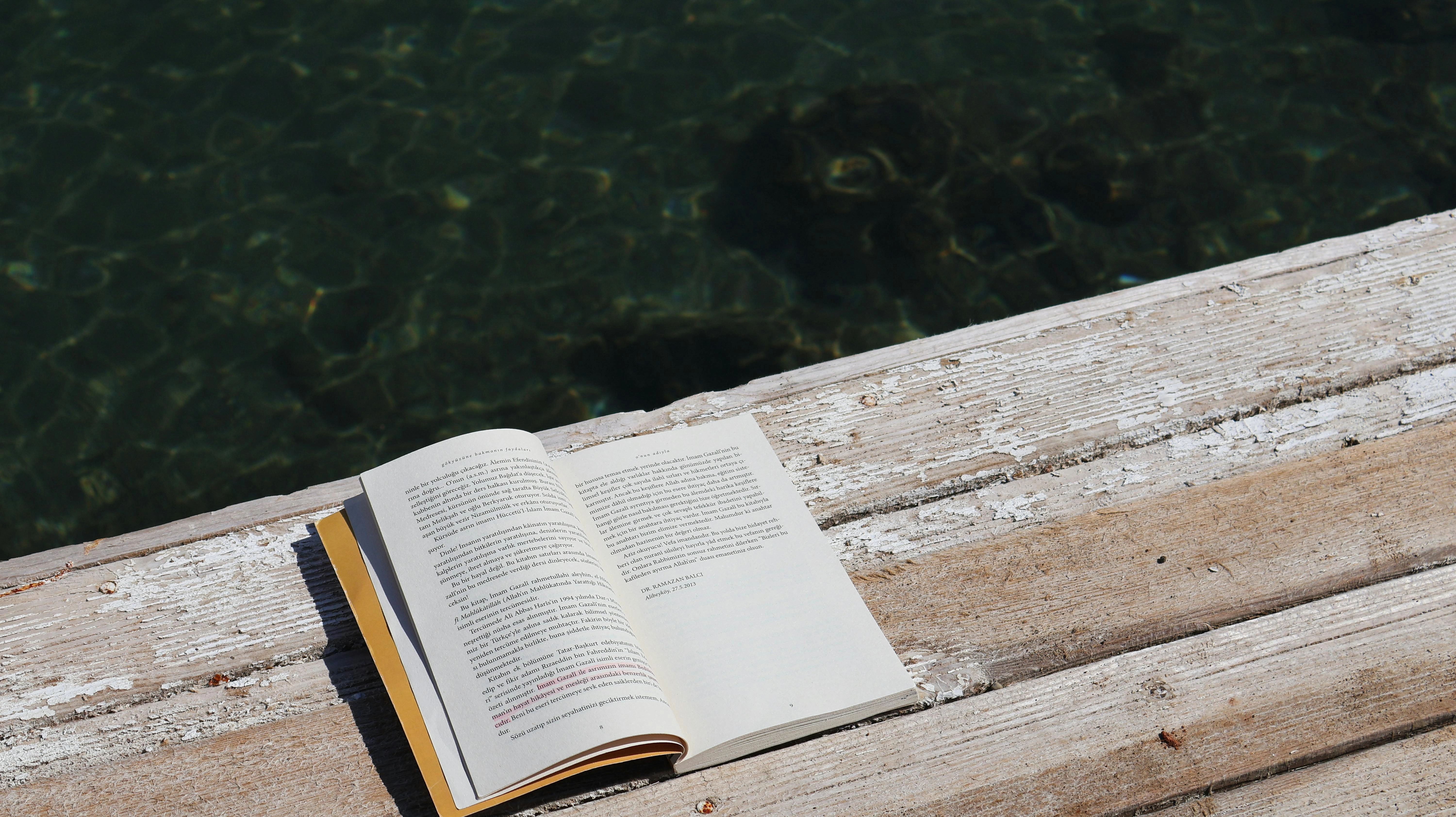 Open book on a wooden deck by the water